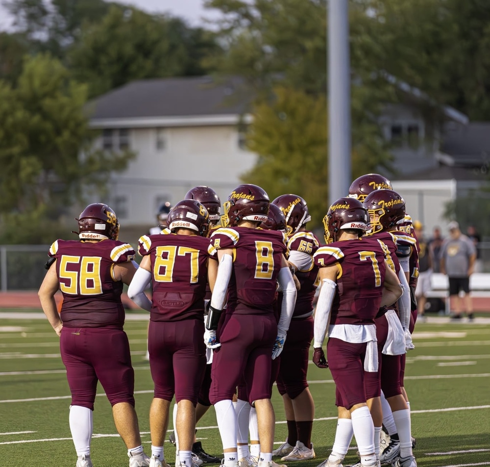 Trojan football team in a huddle before a play